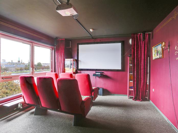 Rum indrettet som biograf med stort lærred og røde biografstole.