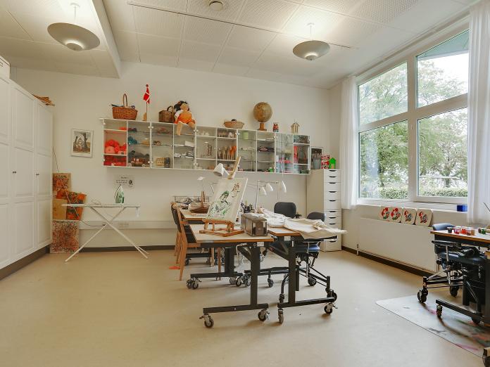 Lyst rum indrettet med forskellige hobbyaktiviteter som maleri og syning.