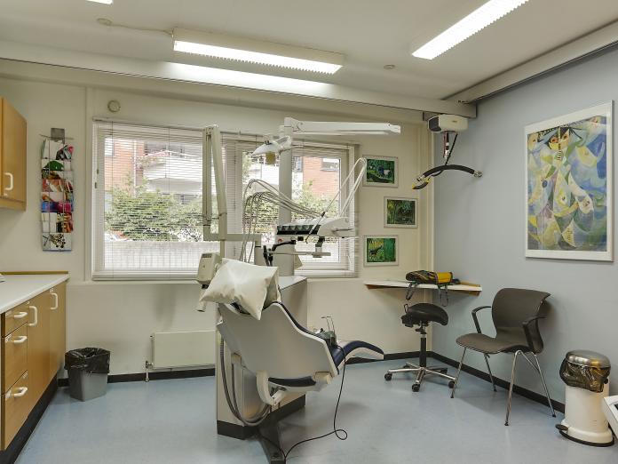 Rum indrettet som tandlægeklinik med loftslift, tandlægestol og bor.
