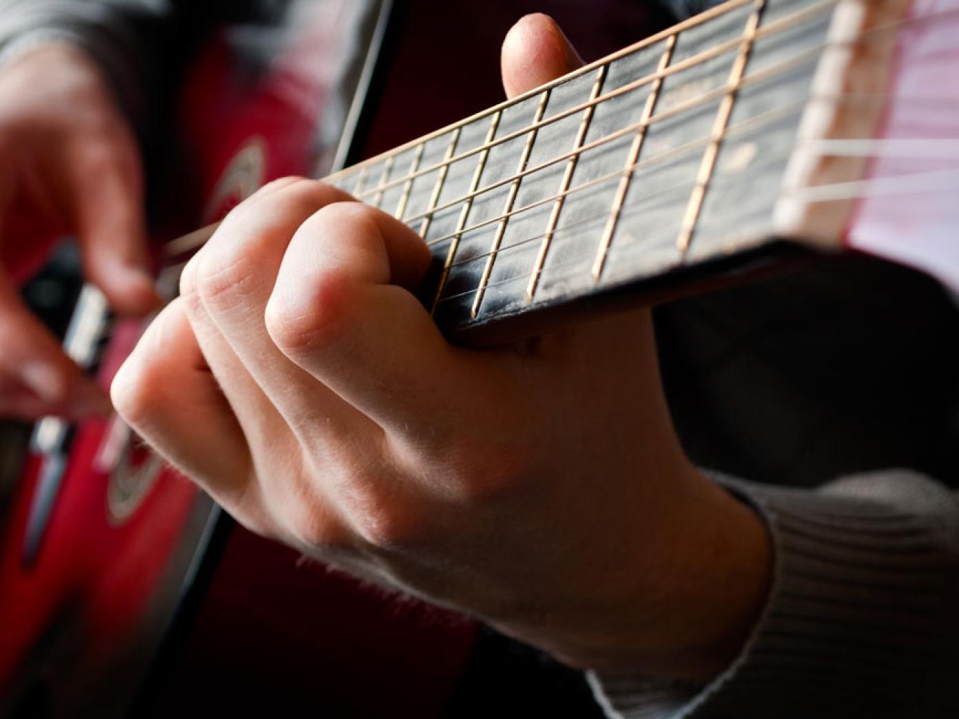 Nærbillede af person, der spiller på guitar.