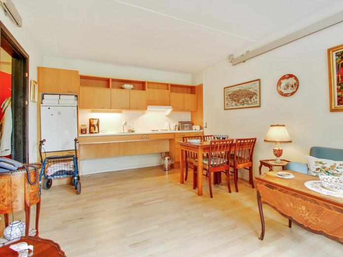 Lys stue med mindre køkken i lyst træ med overskabe, køleskab, vask og kogeplader. Værelset er møbleret med personlige møbler, og værelset har desuden er loftslift.