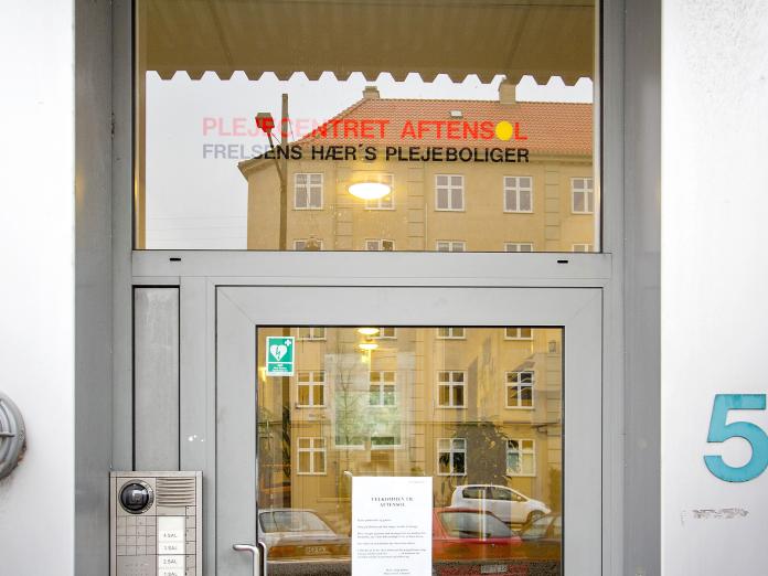 Indgang med dørtelefon og teksten ”Plejecentret Aftensol. Frelsens Hærs plejeboliger.”