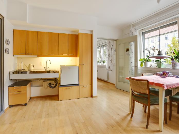 Tekøkken og lille spisebord og dør ind til et andet rum.