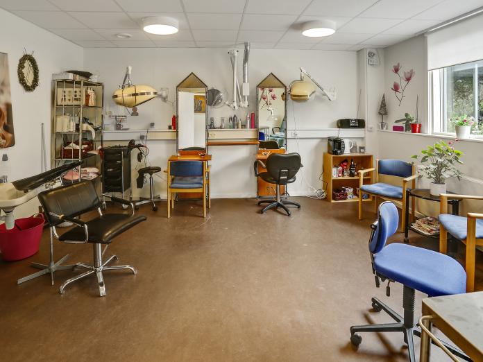 Frisørsalon med to klippestationer med spejl, udluftning og tørrehjelm samt en vaskestation.