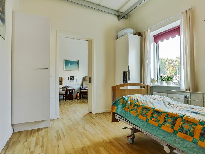 Lyst soveværelse med plejeseng samt to indbyggede skabe og en loftslift.