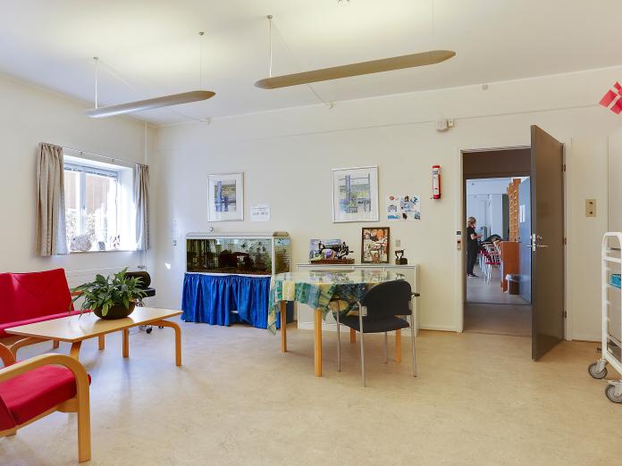 Fælles stue med akvarium, sofaer, sofabord og bord med stole omkring.