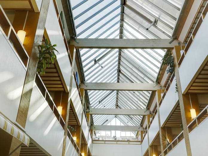Kig fra indre atriumgård og op mod åbne etager og glasloft.