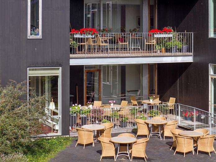 To terrasser med havemøbler og blomster og en fælles altan med havemøbler, og blomster.