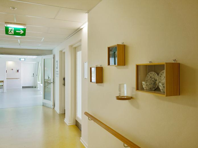 Lang, lys gang med gelænder og sættekasser, hvor historiske artefakter udstillet, som det musselmalede sted. 