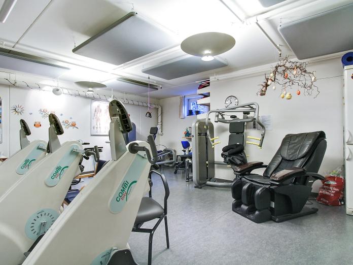 Motionsrum med forskellige træningsmaskiner og en massagestol.
