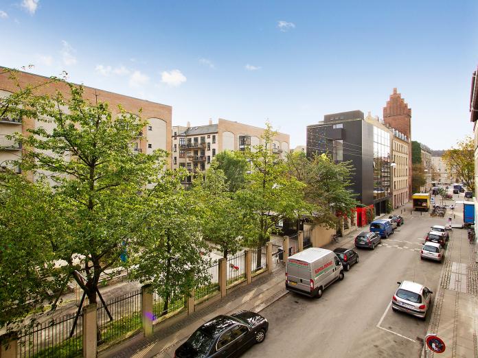 Udsigt fra Rundskuedagens Plejecenter over på park med store, grønne træer.