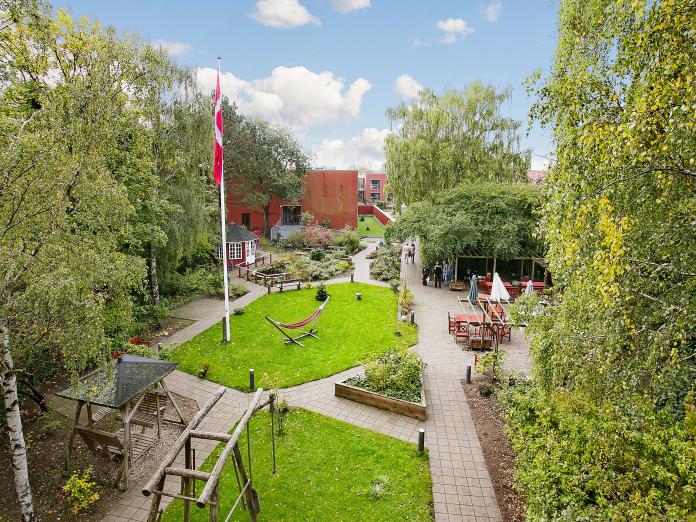 Kig ud over haven, hvor der er flagstang, en gyngesofa, 