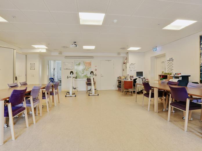 Større aktivitetslokale med siddemotionscykel samt langborde med stole.