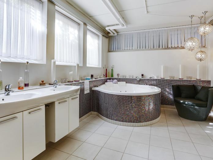 Kurbadsrum med spa/jacuzzi, stearinlys, en kurvestol og orientalske lamper.