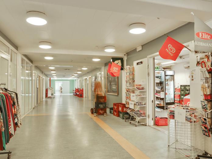 Lang gang med indgang til købmandsbutik.