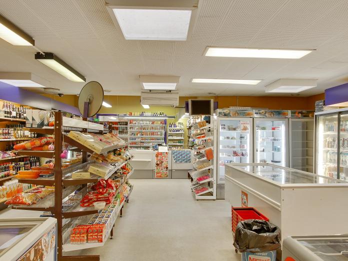 Mindre købmandsbutik med mange forskellige varer på hylderne, kummefrysere og køleskabe.