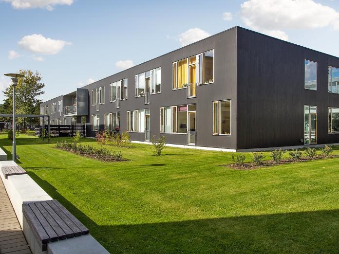 Bomi-Parkens sorte, firkantet bygninger med store vinduespartier, en græsplæne med buske foran.