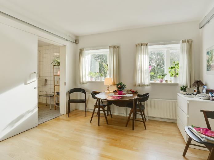 Lyst værelse indrettet med personlige møbler som spisebord med stole og en kommode.