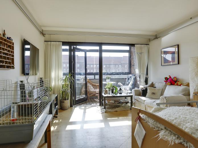 Værelset set fra sengen, hvorfra man gennem store gulv til loft-vinduer kan se ud på en stor overdækket altan.