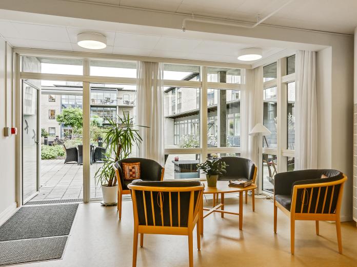 Hyggekrog med lænestole omkring et sofabord. Der er udgang til terrasse gennem terrassedør.