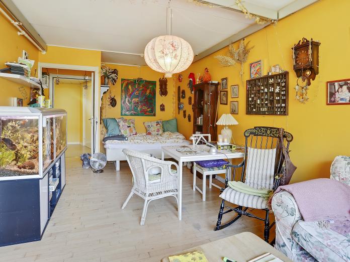 Værelse, der er malet gul, indrettet med loftslift og personlige møbler som seng, akvarium, bord, stole og gyngestol.