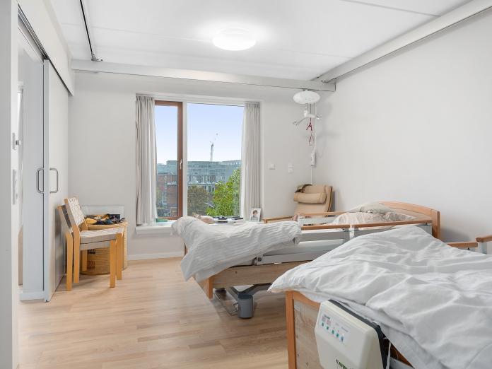 Soveværelse med to plejesenge og loftslift samt stort vindue og skydedør ind til stuen.