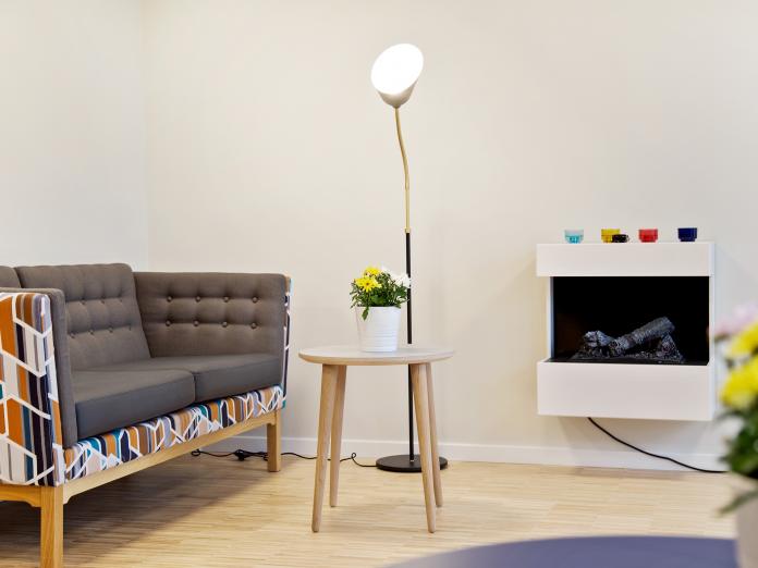 Hyggekrog med sofa, sofabord, standerlampe og elektrisk pejs.