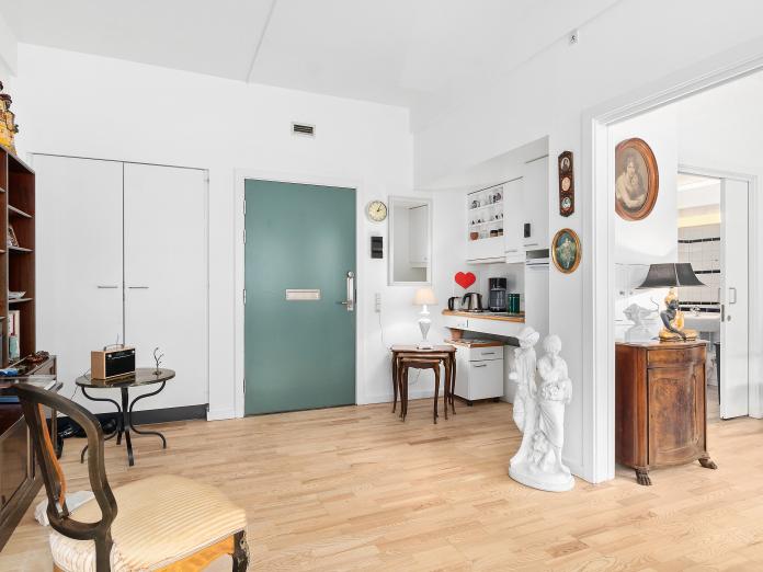 Lys stue med hvidt tekøkken med vask og køleskab samt indbyggede skabe. Fra stuen er der adgang til et soveværelse og derfra et badeværelse.