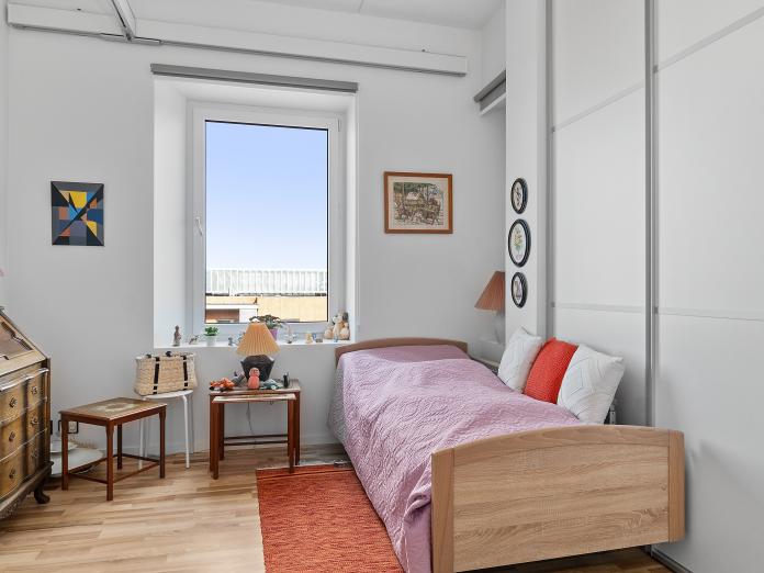 Lyst værelse med plejeseng, loftslift og personlige møbler som chatol og sidebord.