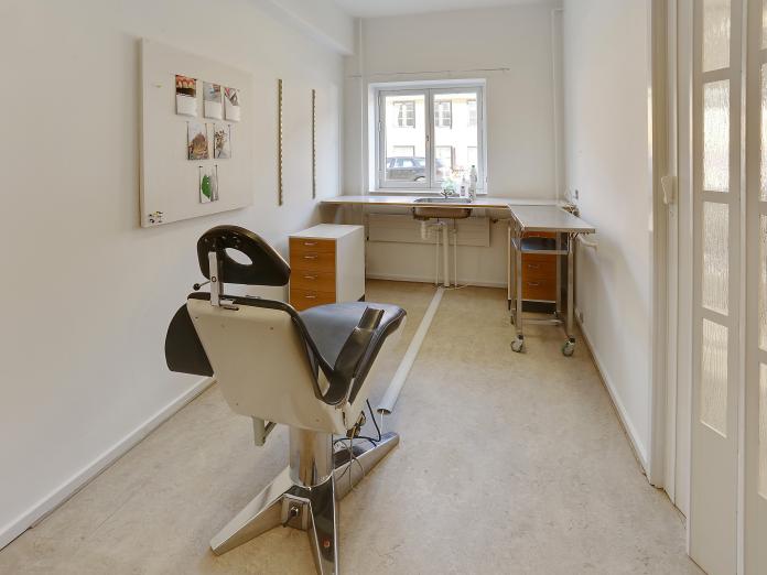 Rum indrettet som klinik med tandlægestol, vask og rulleborde.