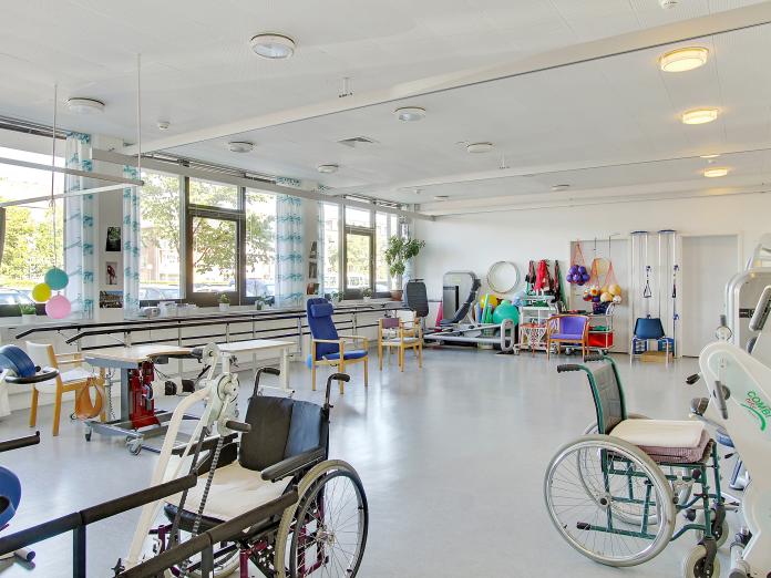 Stort, lyst motionsrum med mange forskellige træningsmaskiner og andre træningsredskaber som pilatesbolde og en hulahopring.