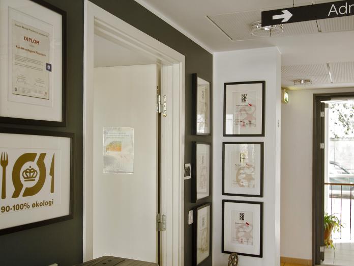 Hjørne af rum, hvor der hænger mange diplomer, som viser, at her laves sund og økologisk mad.