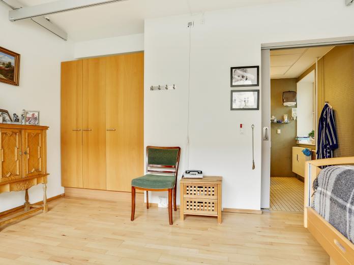 Soveværelse med skab, stol og kig til badeværelset.