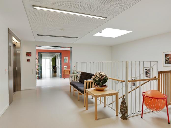 Fællesareal med trappe, elevator og en sofa med sofabord.