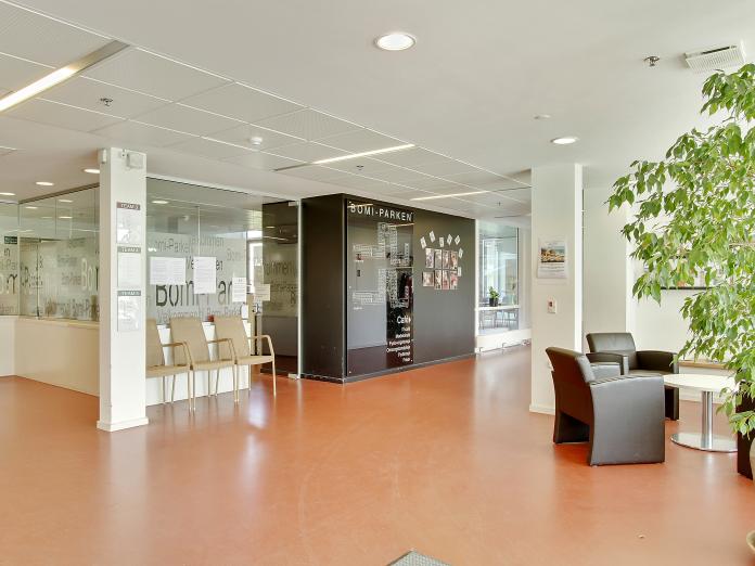 Fællesområde med lænestole, stole og en væg, hvor der står BOMI-PARKEN.