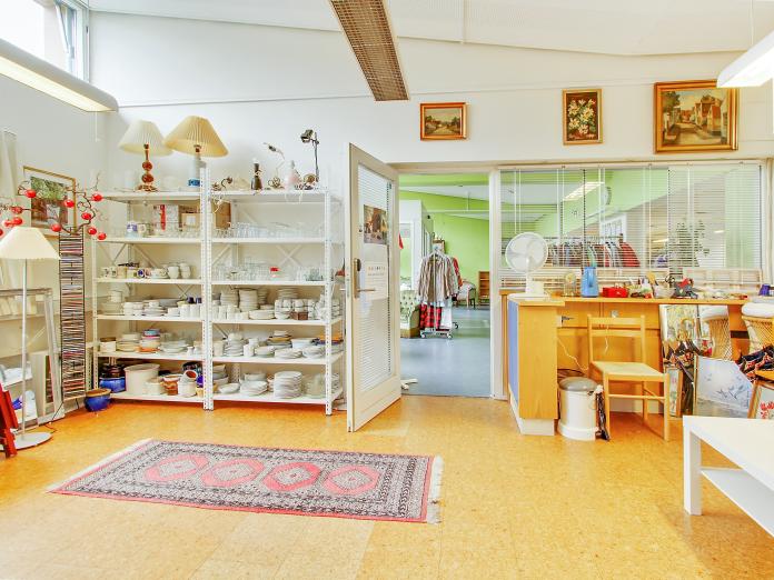 Genbrugsbutikken ”Biksen” med reoler med tallerkener, glas og andet service, lamper, malerier, CD’er.