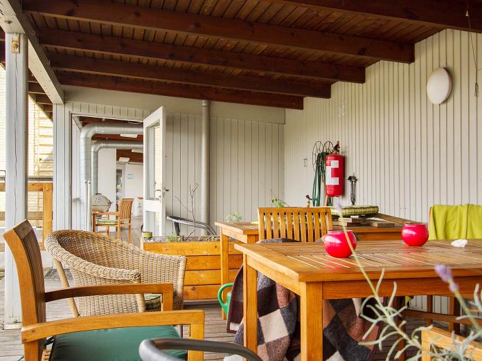 Udendørs, overdækket terrasse med havemøbler i træ. 