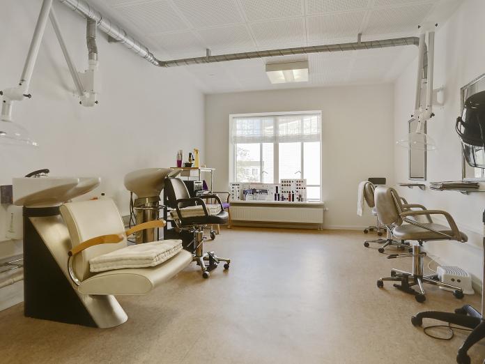 Rum indrettet som frisørsalon med vaskestationer og klippestationer med udsug og tørrehjelme.