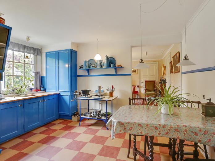 Rum indrettet som køkken fra starten af 1900-tallet med skomagerlamper, gasbord med fliser, Madam Blå kander og skabslåger i almuestil.