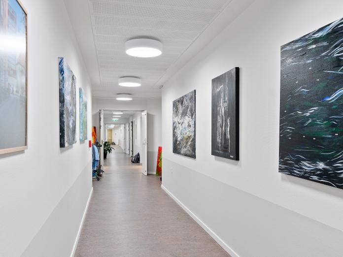 Kig ned langs en lang gang, hvor der hænger malerier på væggene. 