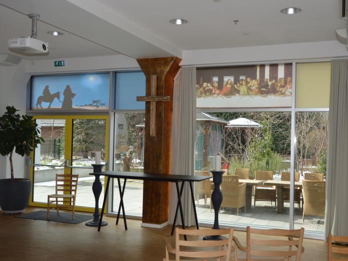 Rum med alter og store lysestager. Der er religiøse motiver og store vinduer med udsigt til haven.