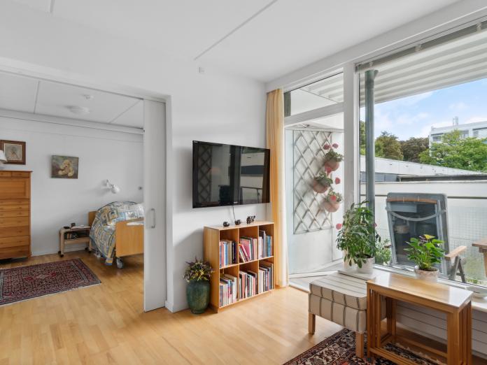 Stue med kig ind til soveværelset og til altanen. Imellem rummene er en åben skydedør. 