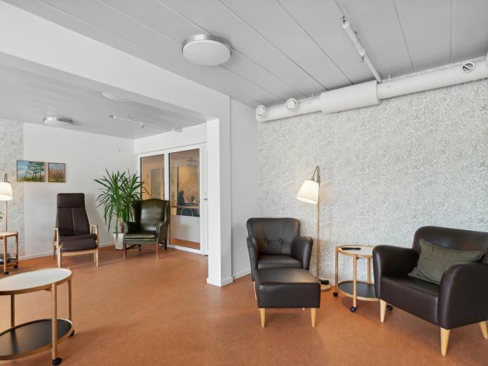 Fælles stue med lænestole og sofaborde.